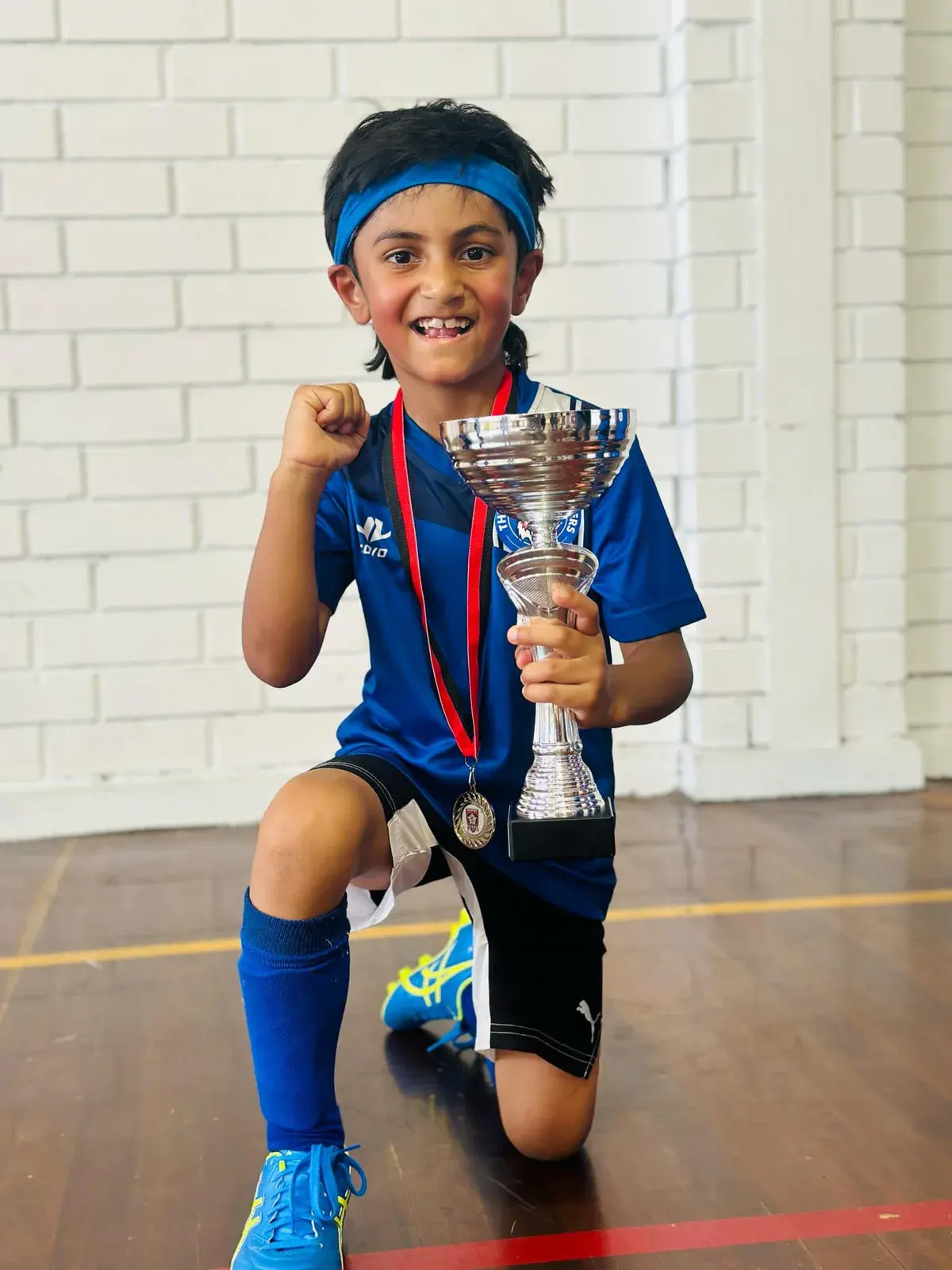 Young player kneeling with a trophy