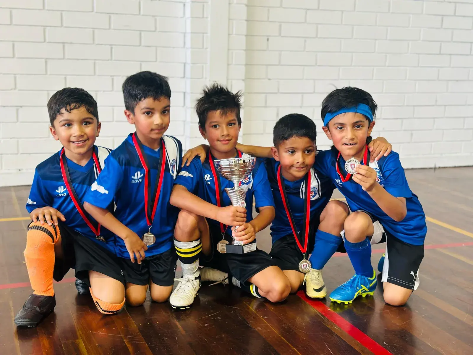 Young teammates sitting together with their trophies