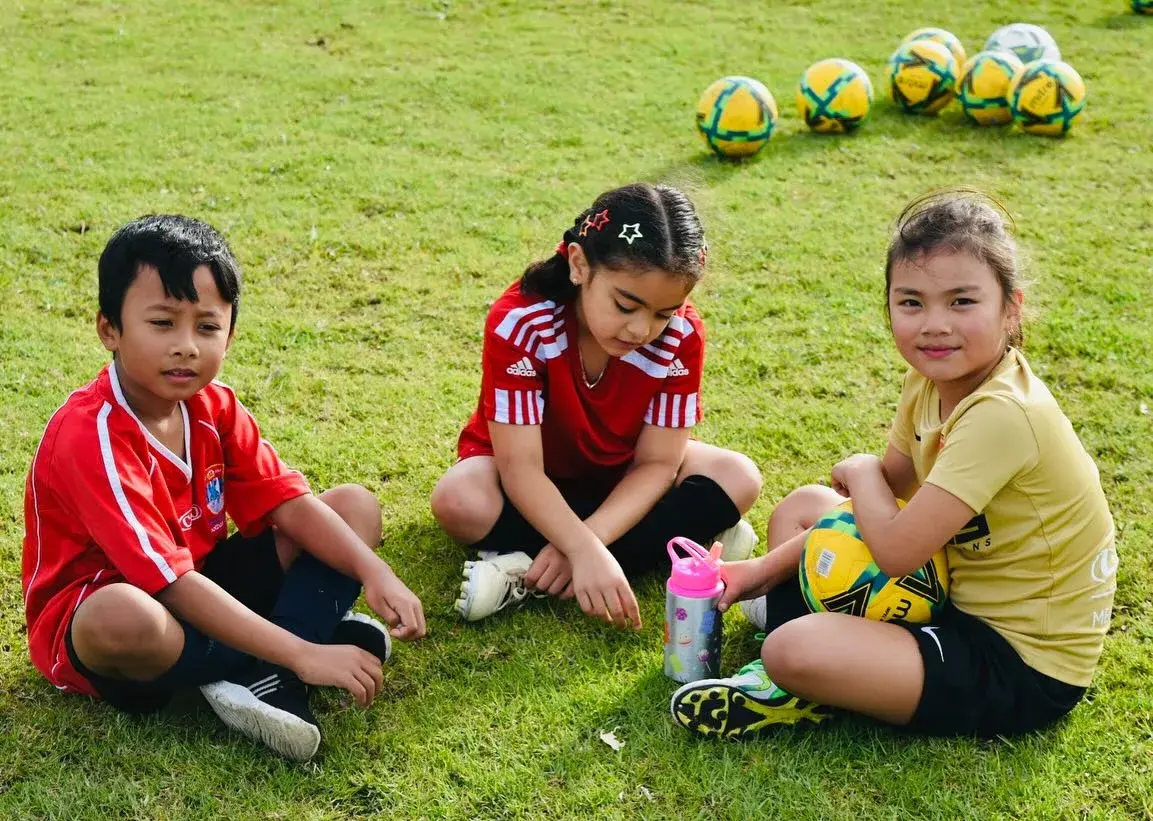 Three children taking a break beside the training balls