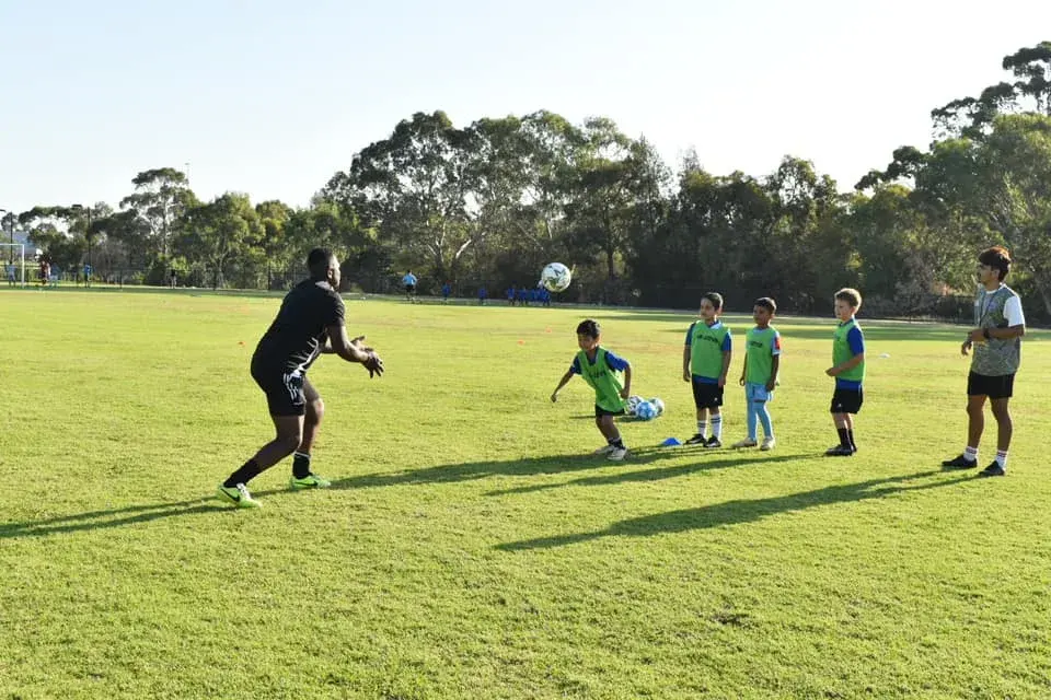 Coach leading a drill with children in training bibs