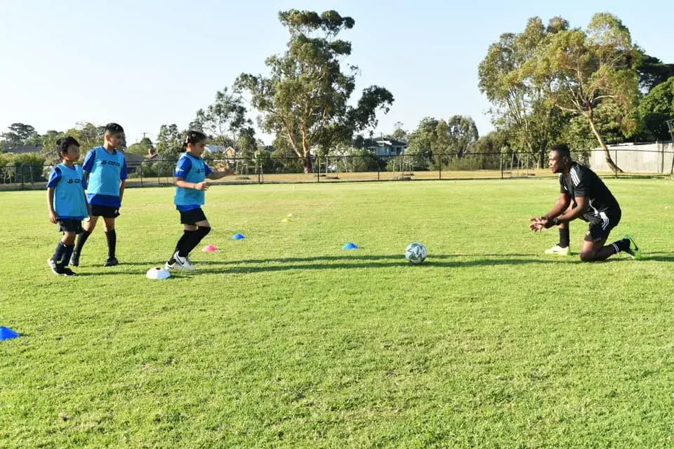 Coach working with young players and footballs