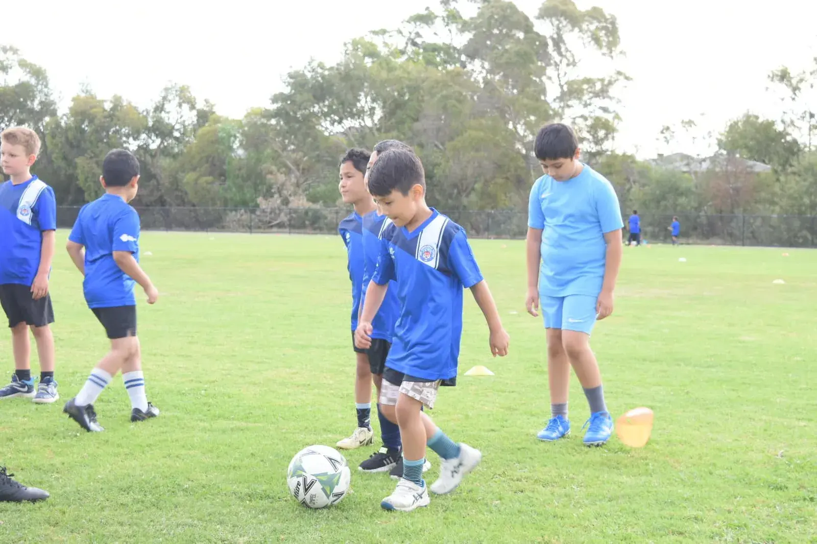 Coach helping children practise ball control