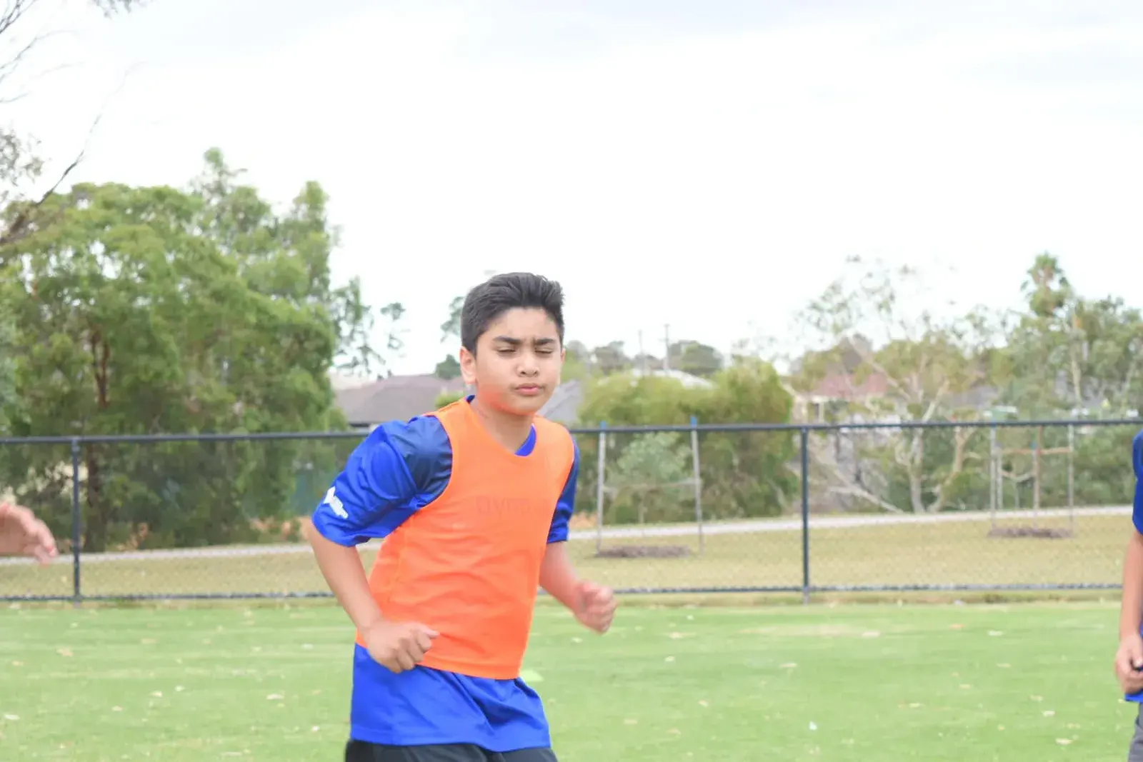 Young player running in an orange training bib